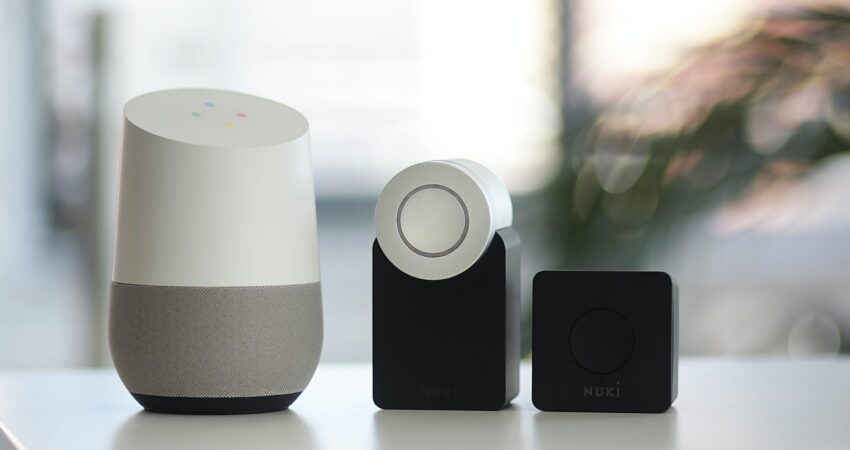 white and gray Google smart speaker and two black speakers